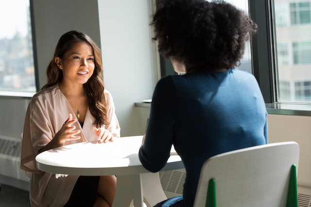 Two people sitting across from each other at a table having a conversation